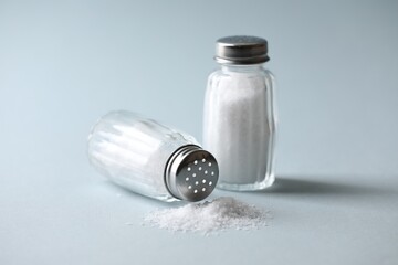 Natural salt in shakers on color background