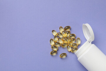 White bottle and vitamin capsules on violet background, top view. Space for text
