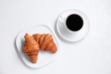 Fresh croissants and coffee on white background, flat lay. Tasty breakfast