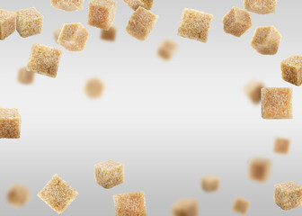 Brown cane sugar cubes falling on grey gradient background