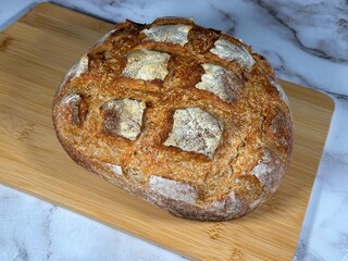Closeup of a freshly baked loaf of sourdough bread, scored in a criss-cross pattern