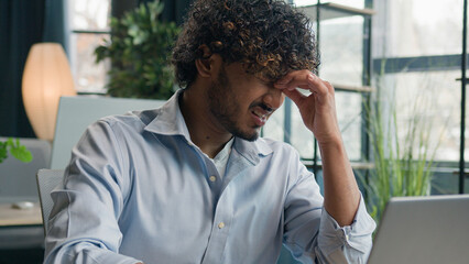 Tired Arabian Indian man sick businessman feel pain eyestrain ache male employee overworked with...