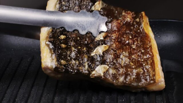 Cooking fillet sturgeon fish on grill or frying pan with oil close-up. Roast healthy food concept. Fry sturgeon, hake, cod fish steak pieces fillet with spice. Healthy diet food