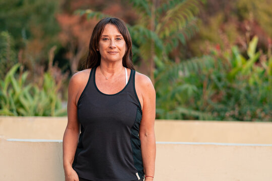 Beautiful senior woman 50 to 60 years old posing in sportswear in an outdoor park at sunset
