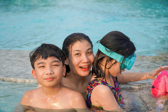 Happy Asian family having fun in swimming pool at the hotel resort. Asian family concept.