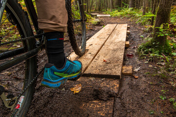 mountain biker peddling over wooden planks in NH White Mountain National Forest, mountain bike...