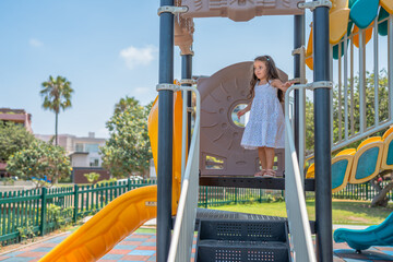 Girl standing wearing summer dress playing in a playground