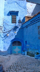 Small, blue, metal door in a blue wall in the medina in Chefchaouen, Morocco