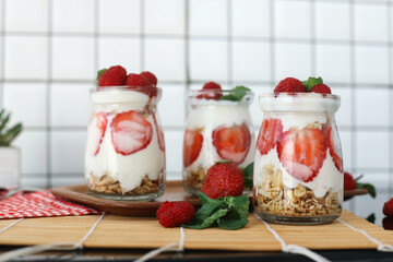Three glasses of strawberry parfaits made with fresh fruit, yogurt and granola on wooden table