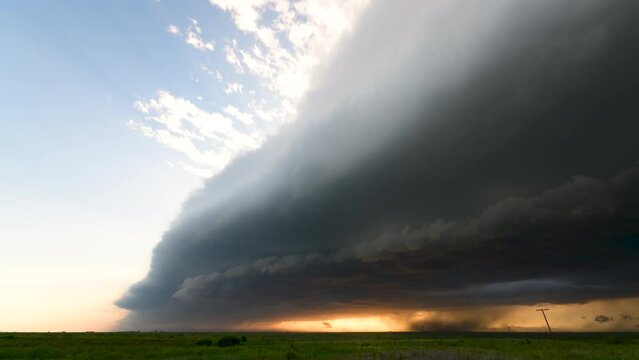 Shelf cloud approaches, packed with wind, rain, and a beautiful sunset.