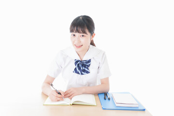机で勉強をする制服姿の女子学生