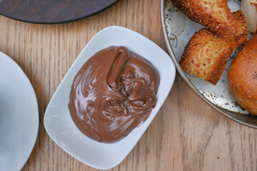a bowl of chocolate cream and bread on a table 