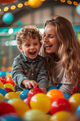 Fototapeta na wymiar Happy child and mother enjoying fun time in ball pit at kids' birthday party