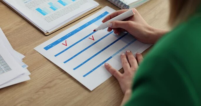 Woman worker draws check marks with marker in planner