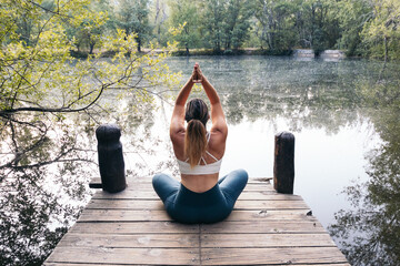 woman in sportswear doing yoga in nature near a lake