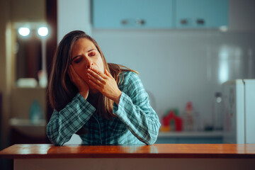 Sleepy Woman Yawning in the kitchen having Insomnia. Unhappy drowsy girl suffering from narcolepsy
