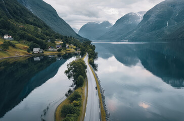 Aerial view of a road along a lake in Norway, with mountains and greenery on both sides