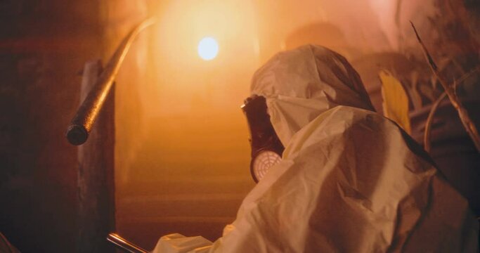 The video depicts a person in a protective suit and holding a gun, standing in a dark nuclear bunker room after a nuclear aftermath, poised defensively to protect himself.