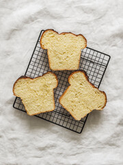 Slice of fresh homemade brioche on a metal baking rack on a light background, top view