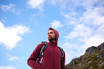 Naklejka premium Blue sky, hiking and man on mountain, thinking and outdoor in nature for adventure, peace and travel. Contemplation, calm and male person in vacation, thoughtful and journey for holiday and backpack