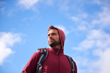 Outdoor, sky and man with backpack, thinking and nature for adventure, peace and travel. Contemplation, calm and male person in trip or vacation, thoughtful and journey for holiday and break