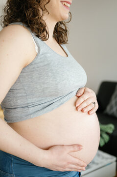 Unrecognizable pregnant woman smiling standing hands on belly