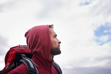 Sky, hiking and man with backpack, thinking and outdoor in nature for adventure, peace and travel. Contemplation, mindfulness and male person looking up, thoughtful and journey for holiday and break