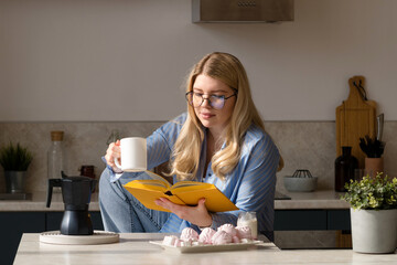 Woman reading book in morning kitchen scene