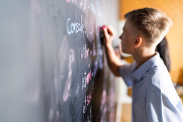 Side view of blonde hair schoolboy wear blue shirt with schoolgirl standing and writing code for...