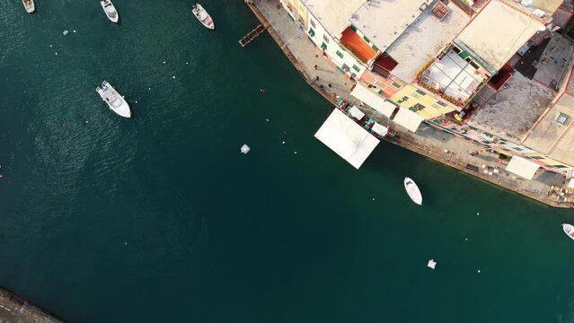 Boats moored in portofino harbor, calm blue waters, vibrant coastal town, aerial view