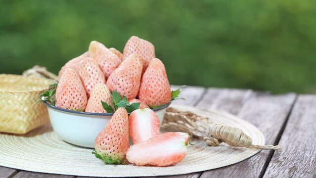 Pink snow strawberry on wooden Table, White and Pink snow Strawberries with slices on  green bokeh background.