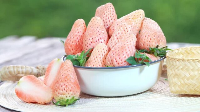 Pink snow strawberry on wooden Table, White and Pink snow Strawberries with slices on  green bokeh background.