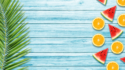 Orange, watermelon and palm leave on blue wooden table. Summer cooking background. 