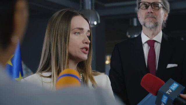 Representative of the European Union at press conference. Confident European female politician answers journalists questions, gives interview for media and television in European Parliament building.