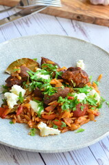 Rice with lamb meat and vegetables on a plate on a wooden table