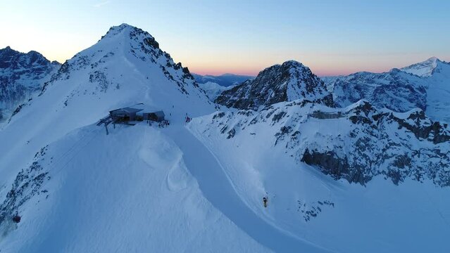 Early morning aerial drone shot over the snowy alps. Camera rising unveiling the majestic mountains chain.