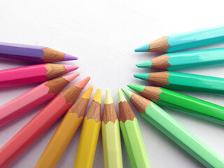 Pastel-colored crayons placed in an arc on white background