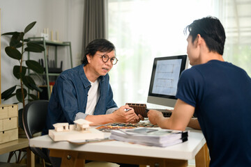 Professional interior designer discussing home renovation project with his client in office