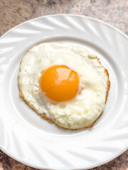 Fried egg on a white plate on the table