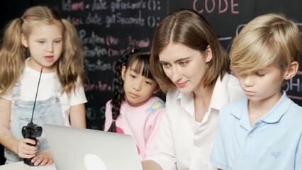 Young smart teacher using laptop to teach diverse student programing system. Caucasian learner...