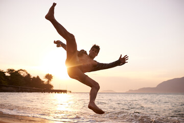 Man, dancing and breakdance with jump on beach for hip hop performance, workout training and practice. Ocean, dancer and movement with energy with sunset, stunt or flexible talent on Maldives holiday