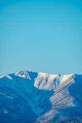 澄んだ青空の下の雪山の稜線と陰影。