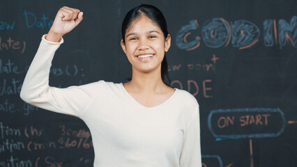 Young student celebrate her successful plan while raise her arm. Happy teenager looking at camera...