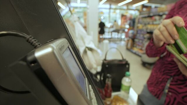 Woman confidently making card payment at self-service checkout close-up slow motion