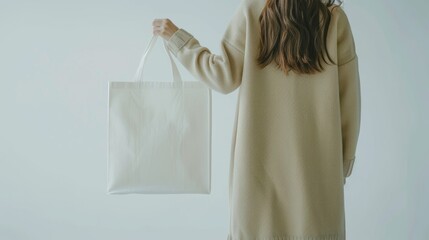 woman holding an empty white bag on a light background, for mockup blank template. Urban mockup of tote bag