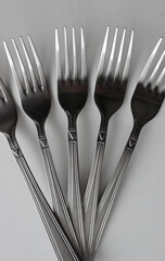 Identical Silvery Forks In A Wing Form On Clean White Surface
