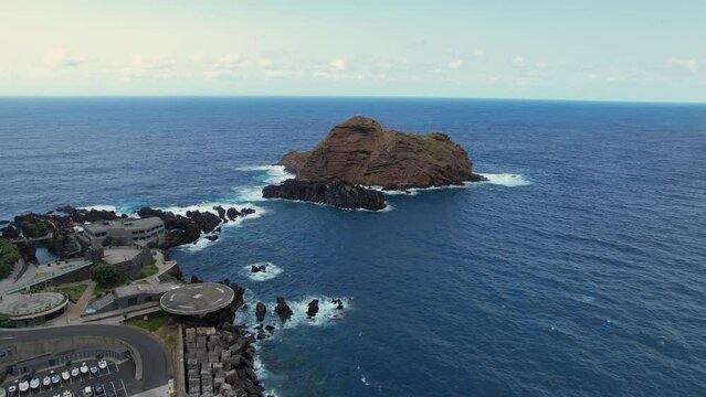 Drone slide reveal Madeira helipad by coastal ocean rock formation