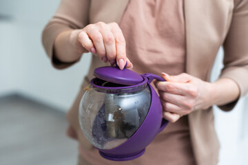 Female hand holding teapot isolated on white background.