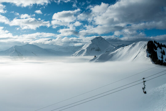 Chairlift over the fog with clouds and blue sky  in the swiss alps