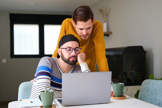 Homosexual couple worried or boring using the laptop at home.